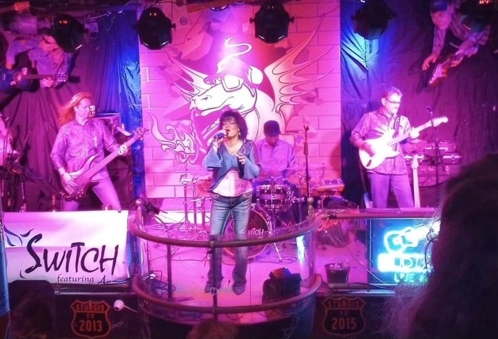 SWITCH featuring Ana performing together under purple stage lights