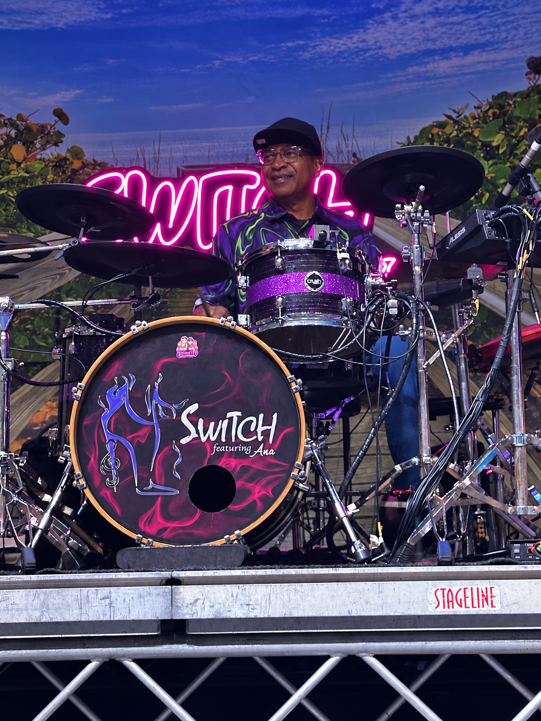 SWITCH drummer performing behind a purple drum kit with the SWITCH featuring Ana logo