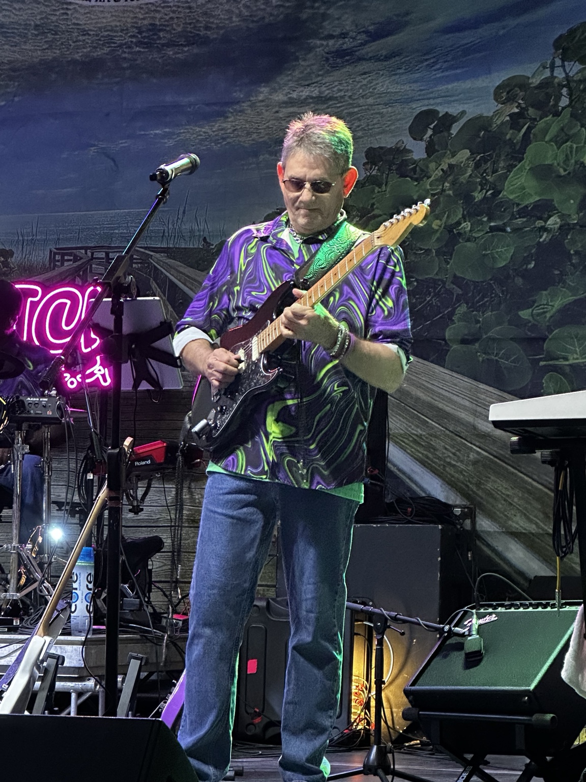 Guitarist playing on stage beside a microphone