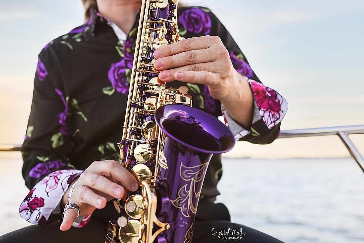 Close-up of a purple and gold saxophone held by a musician